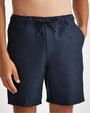 A close-up hip-level view of a shirtless model wearing a pair of navy-blue shorts with an elastic waistband and drawstrings.