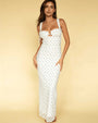A barefoot brunette model standing against a yellow background, wearing a long white form-fitting dress with thin straps and shoulder bows, featuring an empty space design at the chest, and a colorful pattern with a small blue scattered pattern.