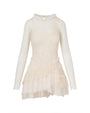 A white dress with a sheer layer over it, creating a sheer neckline and sleeves. The skirt is ruffled with a crisscross fabric design at the waist. The background is plain white.