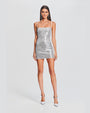 A full body view of a brunette model wearing a short, grey thin strapped dress adorned with shimmering sequins. The model is also wearing long dangly silver earrings with silver heels and is standing in front of a white background.