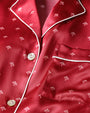 A close-up of a button-down shirt with red fabric, white trim and white buttons, and a small white floral design.