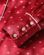 A close-up of a button-down shirt cuff with red fabric and a small white floral pattern, white trim and 3 white buttons.