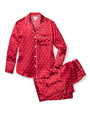 A matching set consisting of a red long-sleeve button down shirt with white polka-dots next to a folded pair of drawstring pants. The background is white.