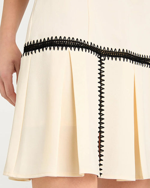 Close-up of a cream-colored skirt with black lace trim on a white background