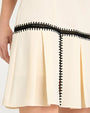 Close-up of a cream-colored skirt with black lace trim on a white background
