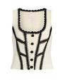 White sleeveless top with black lace and button details on a white background