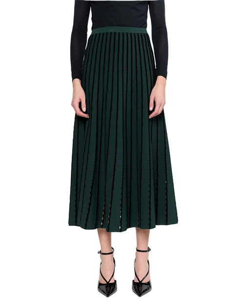Person wearing a green pleated skirt on a white background
