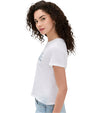 A side view of a curly-haired brunette model wearing a white t-shirt with blue letters on the front paired with blue jeans.