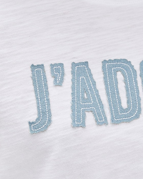 A close-up image of the word "J'AD" written in large, bold blue letters with a slightly worn look on a piece of white fabric.