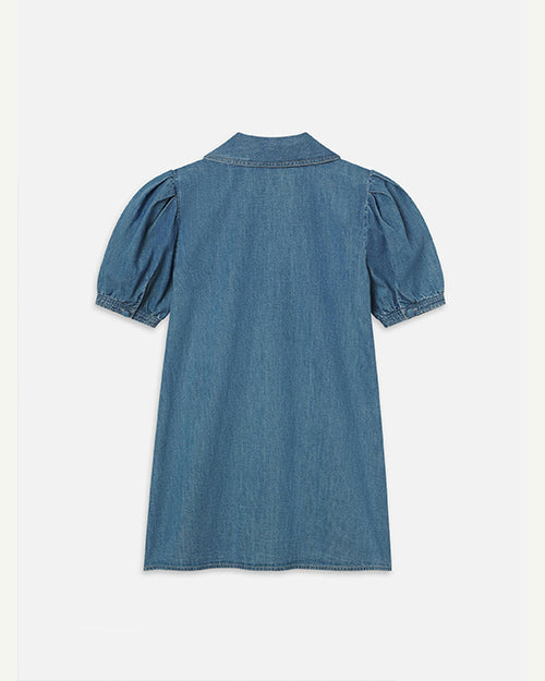 The backside view of a blue denim dress with short, puffed sleeves, a collar, and is placed in front of a white background.
