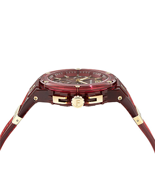 A side view of a burgundy transparent wristwatch with gold accents, including a gold crown with an engraved "F".  The background is plain white.