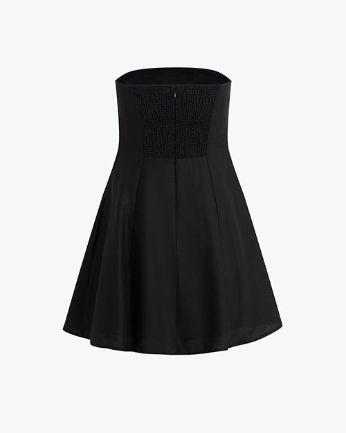 The backside view of a strapless black dress that flares out at the bottom with a zipper running down the back, placed against a white background.