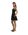 A sideview of a model wearing a strapless black dress that flares out at the bottom. The model is also wearing black pointed-toe shoes and standing against a plain white background.