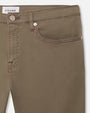 A close-up hip level view of a pair of green jeans with silver buttons, and a white rectangular tag reading "FRAME" on the inner waistline.