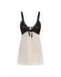 A V-neck dress with thin black straps, black lace detailing, a bow on the upper half, and a white fabric lower section. The background is plain white.