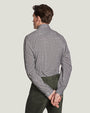 A knee-up backside view of a model wearing a grey long-sleeved shirt tucked into green pants, standing in front of a white background.
