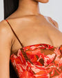 A close-up chest shot of a model wearing a red and brown floral dress with thin straps.