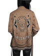 Back view of a person wearing a brown jacket with intricate designs, featuring a large skull with bat-like wings and the word "VOLTAIRE" in stylized text below. The jacket also includes small geometric patterns.