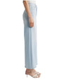 The side view of a person wearing light blue high-waisted wide-leg jeans and white open-toe sandals. The jeans have a button and zipper closure, front and back pockets, and a slightly faded wash.