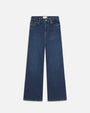 A pair of wide leg blue jeans with a white rectangular tag on the inner waistband. The background is white.