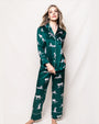 A full body image of a blonde model wearing a matching green long-sleeved button-down pajama set with leopards all over it. The model is standing in front of a white background.