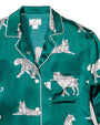 Close up of an emerald, green button-down pajama shirt with a chest pocket, and a white leopard cat pattern. There is a rectangular white tag in the inner neckline. The background is white.