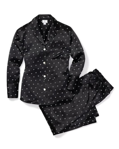 A black button-down pajama set with white polka-dots, next to a folded pair of matching elastic pants. The background is plain white.