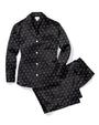 A black button-down pajama set with white polka-dots, next to a folded pair of matching elastic pants. The background is plain white.