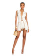 A complete frontal image of a model placed in front of a white background, wearing a sleeveless white vest with beige trim and gold buttons. There are two chest pockets and two hip pockets with button closures. The model is accessorizing with bracelets, a tan bag, and high heels.