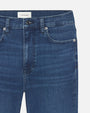 A close-up waist-level view of a pair of blue denim jeans. The jeans have a slightly worn and faded look, particularly around the thighs.