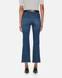 A waist-down backside view of a model wearing a pair of blue denim jeans with a black belt and black heels. The jeans are slightly flared at the bottom.