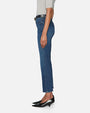 A waist-down sideview of a model wearing a pair of blue jeans with a black belt and black pointed heels. The jeans have a slightly worn and faded look, particularly around the knees and thighs.