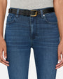 A close-up waist level view of a model wearing a grey shirt tucked into a pair of blue denim jeans with a black belt. The denim has a slightly worn and faded look around the thighs.