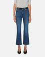 A model is wearing a pair of ankle length blue jeans with a black belt and black shoes. The jeans are slightly flared at the bottom. The denim has a slightly worn and faded look, particularly around the knees and thighs.