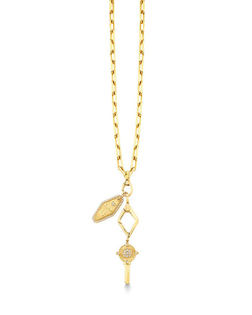 A gold necklace with rectangular chain links, featuring three pendants including a small shield-shaped charm with an engraved design, a diamond-shaped open frame, and an ornate key with intricate detailing at the top. The background is plain white.