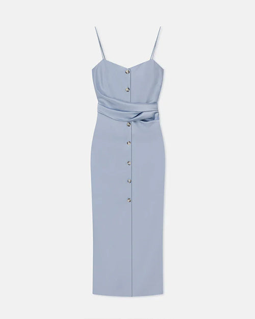 A light blue dress with thin straps behind a white background. The dress has buttons running down the front and light blue fabric tied around the waist, and a seam down the center.