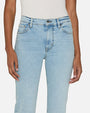 A close-up thigh level view of a person wearing light blue jeans and a white sleeveless top tucked in. The jeans are high-waisted with front pockets and straight legs. The pants have button and zipper closure.