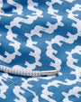A close-up of blue swim shorts material with a repeating pattern of white elephant silhouettes. There is a white drawstring with a metal aglet at its end reading "LOVE BRAND & CO."