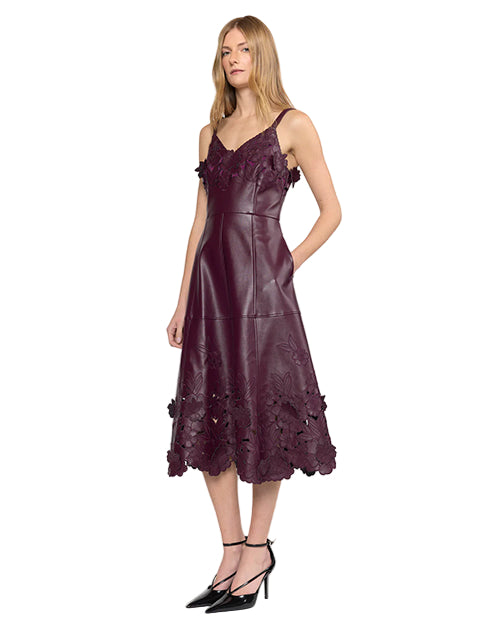 Side view of a person wearing a sleeveless dark purple leather dress with floral lace details, fitted waist, and A-line skirt, paired with black ankle-strap high heels.