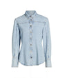 A light blue collared denim shirt with long sleeves and long wrist cuffs. The shirt features visible stitching along the seams and silver buttons. The background is plain white.