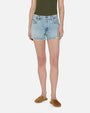 A frontal lower body image of a model wearing a green top tucked into light-wash denim shorts with frayed ends, and brown sandals. The model is standing in front of a white background.