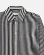 A close-up chest level view of a long-sleeved, button-up shirt with thin navy and white stripes, and a front pocket. The inner neckline has a white tag reading "FRAME".