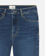 A close-up view of a pair of blue jeans with classic gold stitching. The inner tag reads "FRAME".
