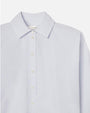 A close-up chest level view of a white and light blue striped long-sleeve button-up shirt. The inside neckline contains a tag that reads "FRAME".