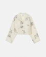 An off-white, long-sleeve button-up pajama shirt in front of a white background. The shirt is off-white with black line drawings of various whimsical characters and scenes such as warriors on horses and towers.
