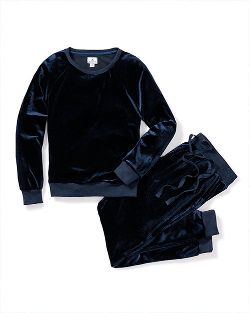 A navy-blue velvet long-sleeved pajama shirt next to a pair of matching folded drawstring pants. The background is plain white.