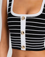 Close-up of a black and white striped crop top with a square neckline, white trim, and three gold buttons down the center.