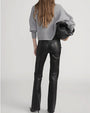 Back view of high-waisted black leather pants paired with a light gray knit cardigan, with the person holding a large black handbag.