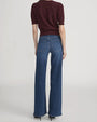 Back view of high-waisted blue wide-leg jeans paired with a short-sleeve textured knit top in deep burgundy and black pointed shoes.
