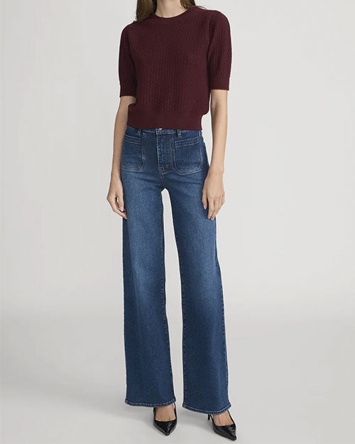 Person wearing a short-sleeve textured knit top in deep burgundy paired with high-waisted blue wide-leg jeans and pointed black shoes.